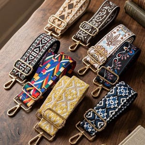 May include: A collection of eight adjustable bag straps featuring various woven patterns in colours including black, white, yellow, blue, red, and brown. Each strap is equipped with gold-toned metal hardware, including rectangular sliders and swivel lobster clasps.