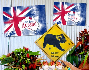 Puede incluir: Una mesa preparada para una fiesta con temática australiana con una variedad de postres y aperitivos. La mesa está decorada con banderas australianas, un cartel que dice "Aussie & Bloody Proud of it!" y un cartel que dice "Next 10 km". Los postres incluyen lamingtons, mini pavlovas, rollos de salchicha y tartas con salsa.