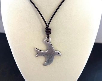 Colgante de pájaro inspirado en Escher sobre cordón de cuero marrón.