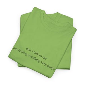 May include: Two lime green t-shirts are stacked on top of each other. The text "don't talk to me, am feeling everthing very deeply" is printed in black on the front of the top t-shirt.