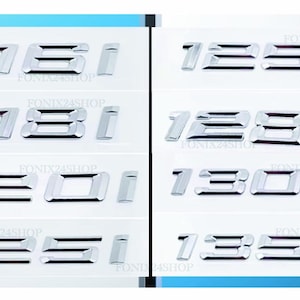 May include: A selection of chrome car model badges, including "116i", "118i", "120i", "125i", "120d", "123d", and "130d", are presented on a white surface. The badges are arranged in a grid.
