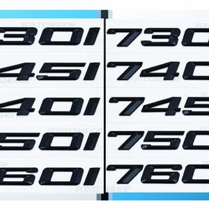 May include: Black car model numbers and letters are displayed on white backgrounds. The numbers include 730, 730d, 745, 740d, 740i, 745d, 750i, 750d, 760i, and 760d. The image is well-lit and the text is clear.