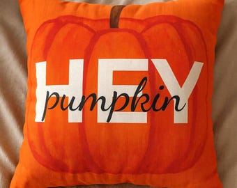 May include: Orange square pillow with a pumpkin design. The pillow features a large pumpkin illustration in shades of orange and red, with the words "HEY pumpkin" in white and black.