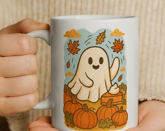 May include: White ceramic mug featuring a cartoon ghost with a smiling face, surrounded by pumpkins, autumn leaves, and a slice of pie. The design has a fall theme with orange, brown, and blue colors.