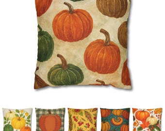 Puede incluir: Un cojín decorativo con un patrón repetido de calabazas en tonos naranja, verde y marrón. Las calabazas tienen superficies texturizadas sobre un fondo crema. Se muestran cojines adicionales con temas otoñales a continuación.