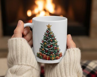 Puede incluir: Taza de cerámica blanca con una ilustración detallada de un árbol de Navidad decorado con adornos y regalos. Una estrella dorada corona el árbol. La taza se sostiene frente a una chimenea.