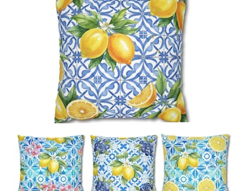 Könnte beinhalten: Quadratische Kissen mit Aquarelldesigns. Das Hauptkissen zeigt ein blau-weißes Fliesenmuster mit Zitronen und grünen Blättern. Andere Kissen haben ähnliche Muster mit Zitronen, Blumen und Blaubeeren.
