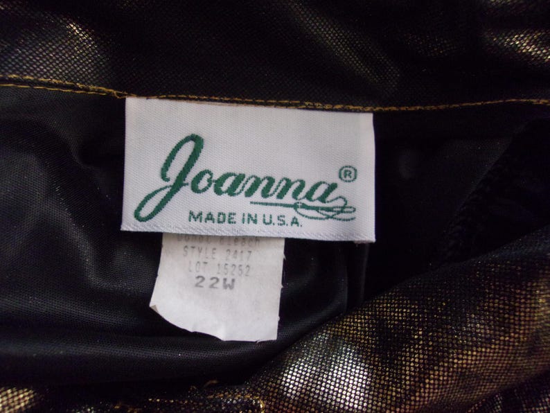 May include: A close-up of a clothing tag with the brand name "Joanna" in a cursive font, with "MADE IN U.S.A." below. The tag also includes style and size information, with a size of 22W.