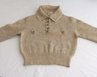 May include: A tan-colored sweater with a collared neckline and long sleeves. The sweater features a button-down front and two decorative buttons on the chest. The cuffs and hem are ribbed.
