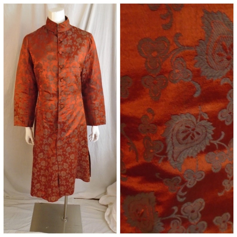 May include: A long, rust-colored robe with a mandarin collar and a floral pattern. The robe has a button closure and is made of a silky fabric.