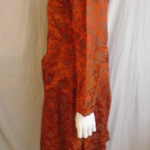 May include: A long, rust-colored robe with a floral pattern. The robe has a mandarin collar and long sleeves.