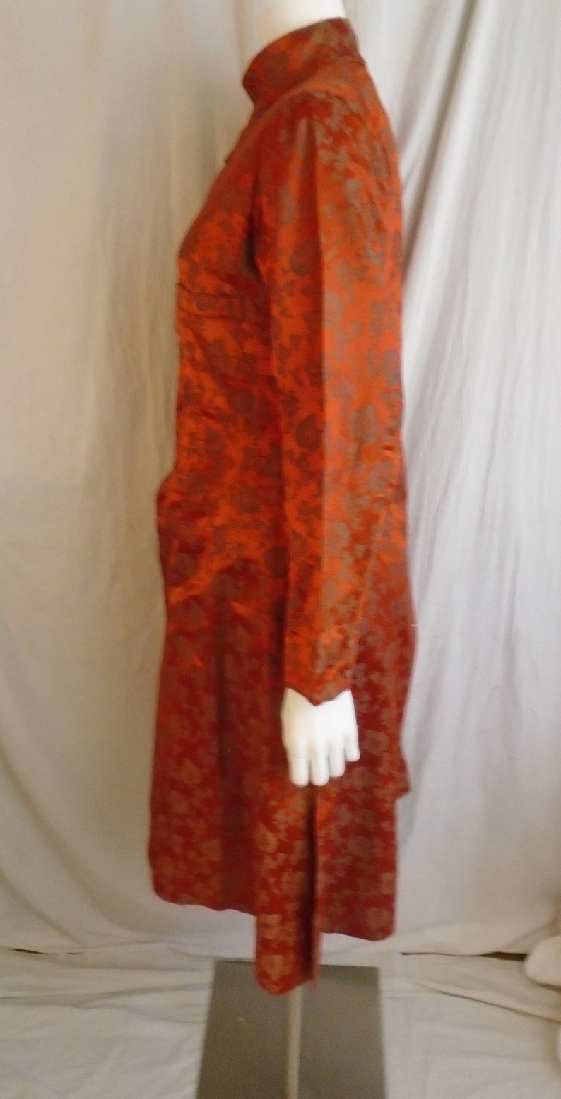 May include: A long, rust-colored robe with a floral pattern. The robe has a mandarin collar and long sleeves.