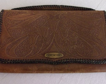 May include: Brown leather clutch with an embossed floral design. The clutch features a decorative metal clasp and a stitched black border. The flap closure and overall design suggest a vintage style, suitable for carrying essentials.