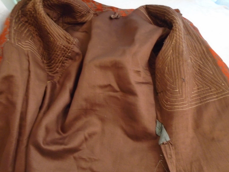 May include: The inside of a brown jacket with a quilted lining. The lining is a lighter brown color and has a geometric pattern.