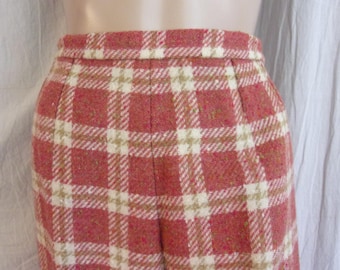 May include: Close-up of a pair of high-waisted, vintage-style trousers. The fabric features a red and cream plaid pattern with a subtle texture. The trousers have a tailored fit, with pleats at the waist.