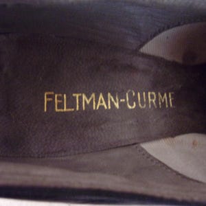 Peut inclure: Gros plan de l'int&eacute;rieur d'une chaussure marron fonc&eacute;. Le nom de la marque "FELTMAN-CURME" est imprim&eacute; en lettres dor&eacute;es sur la semelle int&eacute;rieure. L'int&eacute;rieur de la chaussure est d'une nuance de marron plus fonc&eacute;e.