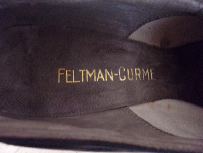 Peut inclure: Gros plan de l'int&eacute;rieur d'une chaussure marron fonc&eacute;. Le nom de la marque "FELTMAN-CURME" est imprim&eacute; en lettres dor&eacute;es sur la semelle int&eacute;rieure. L'int&eacute;rieur de la chaussure est d'une nuance de marron plus fonc&eacute;e.