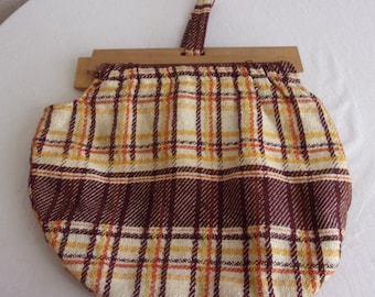 Peut inclure: Un sac à main en tissu à carreaux brun et beige avec une armature en bois et une anse en tissu brun.