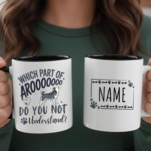 May include: Two white ceramic mugs with black rims and handles are held up. One mug has the text "WHICH PART OF AROOOOOOO DO YOU NOT UNDERSTAND?" with a dog illustration. The other mug has the text "NAME" inside a paw print and bone border.