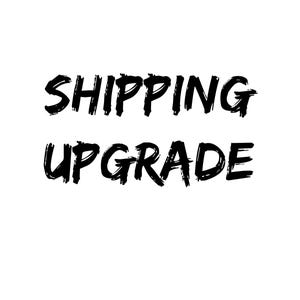 May include: A graphic design featuring the text SHIPPING UPGRADE in a bold, black, brush-stroke style font against a plain white background. The letters have a textured, hand-painted appearance with uneven edges and varying line thickness throughout.
