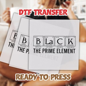 May include: Three white DTF transfer sheets with the word "BLACK" spelled out using elements from the periodic table. The text "THE PRIME ELEMENT" is below the word "BLACK". The words "DTF TRANSFER" and "READY TO PRESS" are also visible.