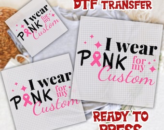 May include: Three DTF (Direct to Film) transfer sheets with the text "I wear PINK for my Custom". The text is in black and pink, with a pink ribbon graphic. The words "DTF TRANSFER" and "READY TO PRESS" are also visible.