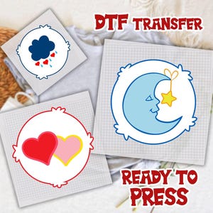 May include: DTF transfer designs featuring cartoon graphics. Designs include a blue cloud with rain and hearts, two hearts, and a blue moon with a star. The text "DTF TRANSFER" and "READY TO PRESS" are also visible.