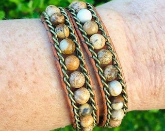 May include: A double-wrap leather bracelet with brown and white beads and gold metal accents.