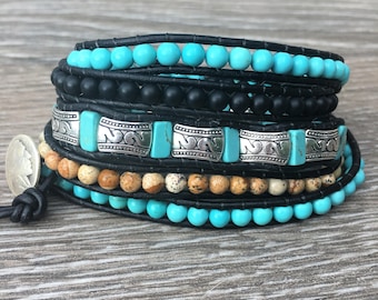May include: A multi-strand bracelet with turquoise, black onyx, and brown jasper beads. The bracelet features silver spacers with a decorative design. The bracelet is wrapped around a wooden surface.