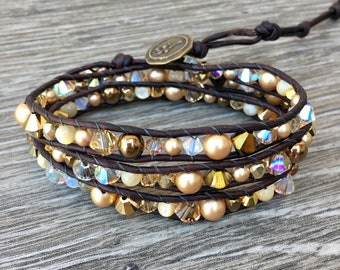 May include: A multi-strand leather wrap bracelet with gold and clear beads. The bracelet has a brown leather cord with a metal clasp.