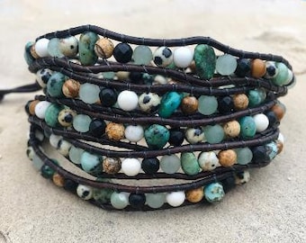 May include: A multi-strand leather wrap bracelet with turquoise, white, and brown beads. The bracelet is made with a variety of natural stones and glass beads.