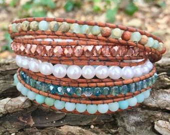 May include: A multi-layered bracelet with brown leather cord and various beads, including light green, white, and blue beads.
