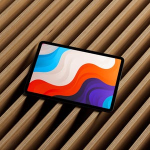 May include: A black tablet with a colorful abstract design on the screen, featuring flowing shapes in shades of blue, white, orange, and purple. The tablet is positioned on a wooden slatted surface.