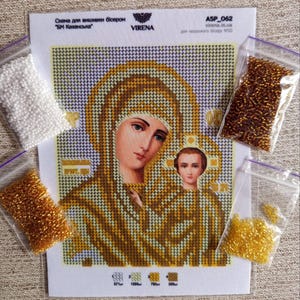 Könnte beinhalten: Ein Bastelset für Perlenstickerei mit einem religiösen Bild der Jungfrau Maria und des Kindes. Das Bild ist auf Stoff mit einem Rastermuster gedruckt. Kleine Beutel mit Perlen in verschiedenen Farben, darunter Gold, Braun und Weiß, sind enthalten. Der Text "VIRENA" ist sichtbar.