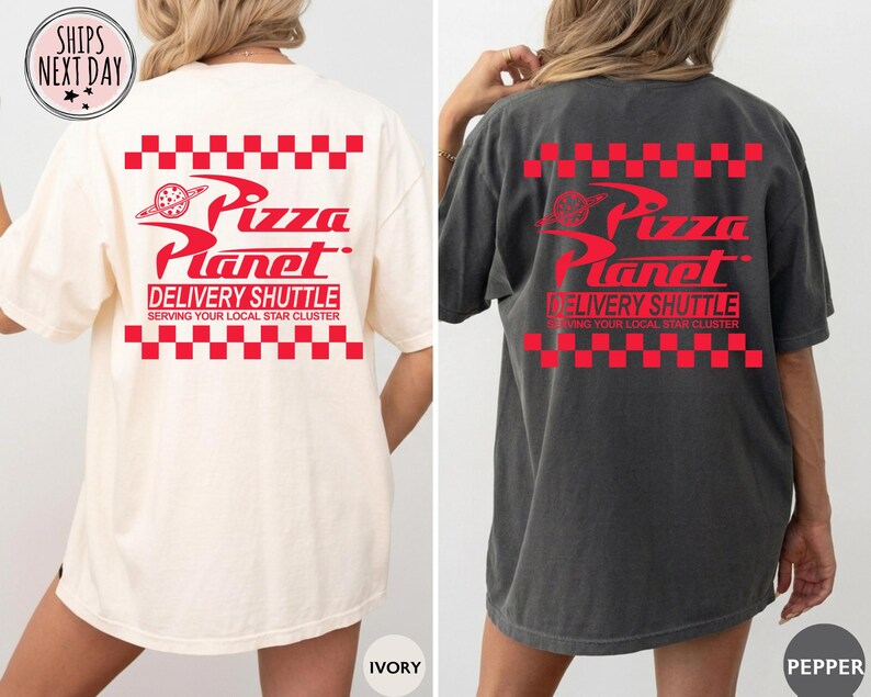May include: Ivory and pepper-coloured t-shirts with the Pizza Planet logo in red. The design includes the text "Pizza Planet Delivery Shuttle" and "Serving Your Local Star Cluster" with a red checkered pattern.