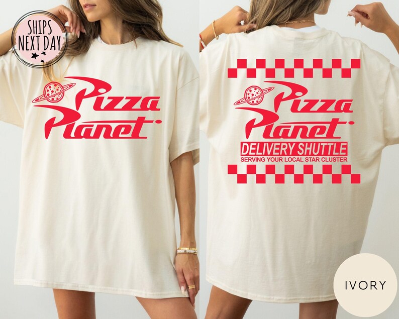 May include: Ivory t-shirt featuring the red "Pizza Planet" logo on the front and back. The back design includes "DELIVERY SHUTTLE" and "SERVING YOUR LOCAL STAR CLUSTER" text, with a red and white checkered pattern.
