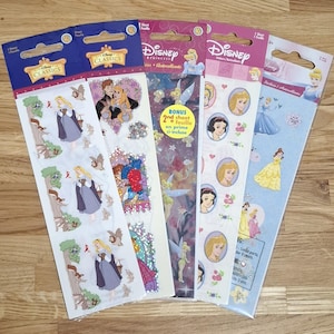 Puede incluir: Cinco paquetes de pegatinas de princesas Disney. Las hojas de pegatinas presentan varias princesas, como Aurora, Cenicienta y Blancanieves. El embalaje incluye los logotipos de Disney Classics y Disney Princess. Las pegatinas son coloridas y presentan varias escenas y personajes.