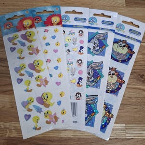 Puede incluir: Varias hojas de pegatinas de Looney Tunes con personajes como Piolín, Bugs Bunny y el Demonio de Tasmania. Las pegatinas son coloridas y presentan varias formas y diseños, ideales para decorar cuadernos o manualidades.