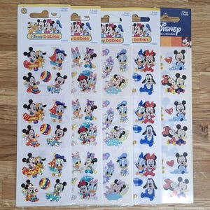 Puede incluir: Cuatro hojas de pegatinas de Disney Babies con Mickey Mouse, Minnie Mouse, Donald Duck y Daisy Duck. Las pegatinas tienen un acabado brillante y representan a los personajes en varias poses. El embalaje incluye el logotipo de Disney Babies.
