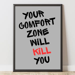 May include: Framed print with the text "YOUR COMFORT ZONE WILL KILL YOU" in black and red on a gray background. The black frame surrounds the motivational quote, suitable for home or office decor.