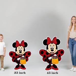 May include: Two Minnie Mouse character cutouts featuring a red and black polka dot dress, a red bow, and a yellow treat bag. The smaller cutout is labeled 35 inch and the larger cutout is labeled 45 inch, indicating their respective heights.