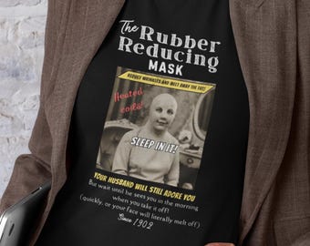 May include: Black t-shirt with a vintage advertisement for "The Rubber Reducing Mask." The ad promises to reduce wrinkles and melt away fat with heated coils. The text includes "Sleep in it!" and a warning about the morning appearance. Since 1902.