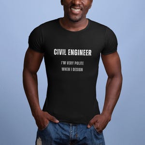 Könnte beinhalten: Schwarzes T-Shirt mit dem Text "CIVIL ENGINEER" und dem Satz "I'M VERY POLITE WHEN I DESIGN" in Weiß. Das T-Shirt wird von einer Person in blauen Jeans getragen.