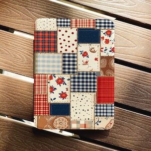 May include: A patchwork design with squares of diverse patterns and colours, including red plaid, blue gingham, and floral prints. The design also features solid navy blue squares and dotted patterns. The overall aesthetic is reminiscent of a quilt.