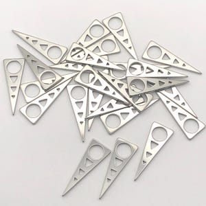 May include: A pile of silver metal triangle charms with a circle cut out in the center. The triangles have a pointed tip and a small hole at the top.