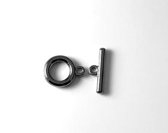 Op de afbeelding: Zilverkleurige metalen toggle sluiting met een ronde ring en een rechte staaf. De sluiting wordt gebruikt voor het maken van sieraden.