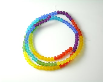 May include: A strand of rainbow colored glass beads. The beads are matte and have a faceted finish. The beads are strung on a clear thread.
