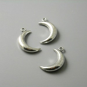 May include: Three silver crescent moon charms with a loop at the top for attaching to jewelry or other crafts.