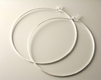 May include: A pair of silver hoop earrings. The hoops are large and circular, with a simple, minimalist design.