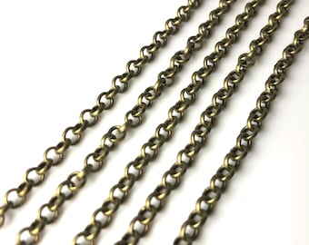 May include: Four strands of gold-toned metal chain, each with a different length, are laid out on a white surface. The chains are made of small, round links.